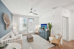 A living room with a white couch, a blue cabinet, and a ceiling fan.