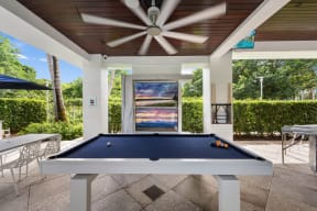 a pool table in a patio area with a ceiling fan