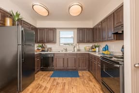 A kitchen with wooden cabinets and a black refrigerator.