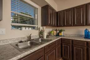 A kitchen with brown cabinets and a stainless steel sink.