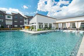 a swimming pool with lounge chairs and umbrellas in front of a building