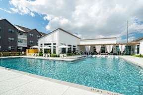 a large swimming pool with umbrellas and chairs in front of a building