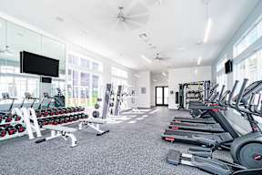 a spacious fitness room with cardio equipment and a flat screen tv