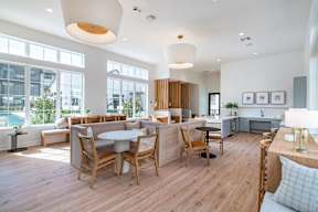 a communal area with tables and chairs and a pool in the background
