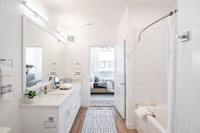 a small bathroom with white cabinets and a white bathtub