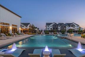 a swimming pool with lounge chairs and umbrellas in front of a building