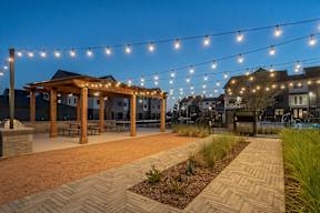 a patio with string lights and a wooden gazebo