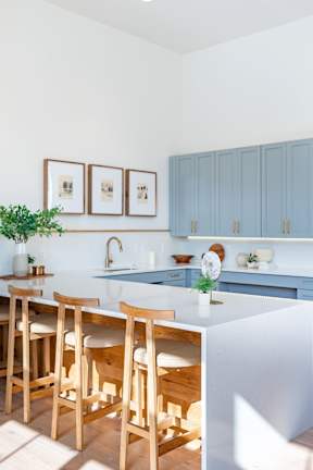 a kitchen with blue cabinets and a white island with wooden stools