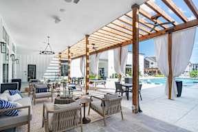 a rendering of a patio area with chairs and tables and a pool in the background