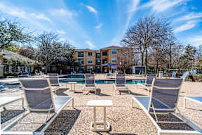 a pool with lounge chairs and a building in the background