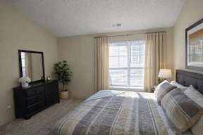 A bedroom with a large bed and a dresser with a mirror.