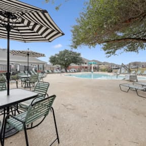 A patio with a table and chairs under an umbrella.