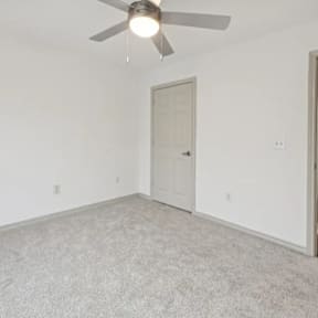 A room with a ceiling fan and carpeted floor.