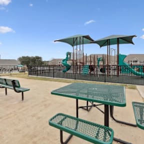 A playground with a green slide and a table with green chairs.