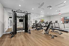 a gym with treadmills and other exercise equipment on a wooden floor