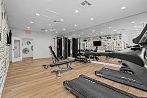 the gym with treadmills and other exercise equipment in a room with white walls