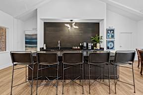 a kitchen with a bar and chairs in front of a wood floor