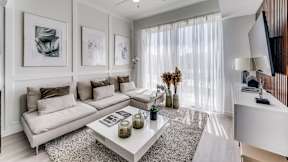 A living room with a white sofa, a coffee table, and a television.
