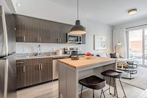 A modern kitchen with a wooden island and stools.