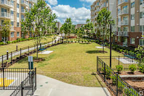 A black metal fence surrounds a small park with a playground.