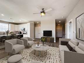 A modern living room with a white sofa, grey armchairs, and a patterned rug.