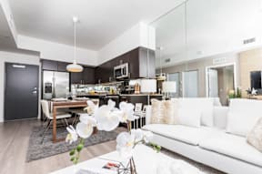 A modern living room with a white couch and a dining table with chairs.