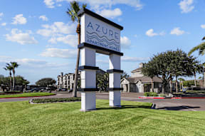 A sign for Azure Apartment Homes stands in a grassy area.