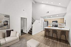 A modern kitchen with a breakfast bar and a staircase.