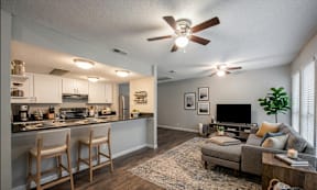 A well-lit kitchen and living room with a ceiling fan.