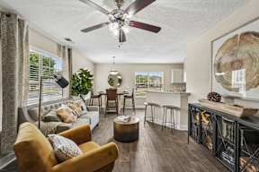 A living room with a yellow chair and a ceiling fan.