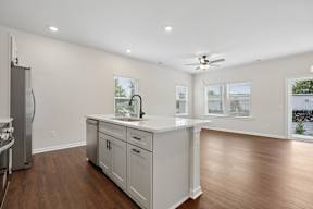 A kitchen with white cabinets and a wooden floor.
