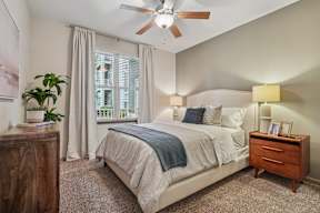 A bedroom with a bed, nightstand, and a ceiling fan.
