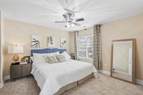 A bedroom with a bed, nightstand, and a ceiling fan.
