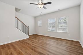 A room with a ceiling fan and wooden flooring.