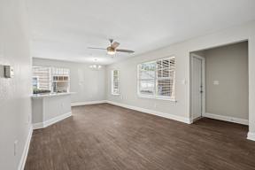 A room with a ceiling fan and wooden flooring.