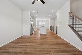 A long hallway with a ceiling fan and wooden floors.