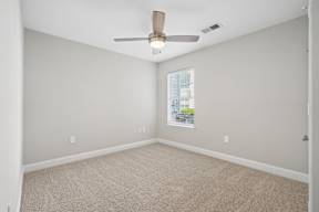 A room with a ceiling fan and carpeted floor.