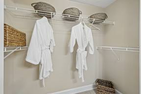 Two white bathrobes hanging on a rack in a room.