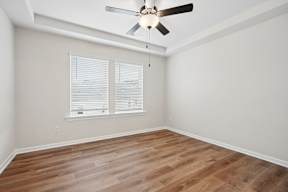A room with a ceiling fan and wooden flooring.