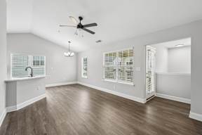 A room with a ceiling fan and wooden flooring.