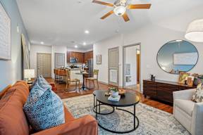 A living room with a brown couch and a round mirror on the wall.