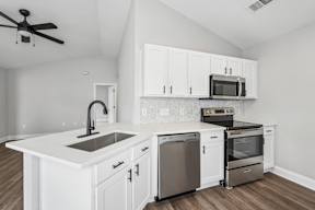 A modern kitchen with white cabinets and stainless steel appliances.