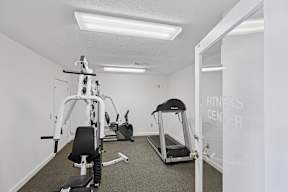 A fitness center with a treadmill, a weight machine, and a leg press machine.