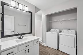 A bathroom with a white sink and two white washing machines.