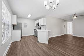 A kitchen with white cabinets and a wooden floor.