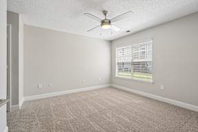 A room with a ceiling fan and carpeted floor.