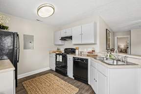 A kitchen with white cabinets and black appliances.