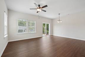 A room with a ceiling fan and wooden flooring.