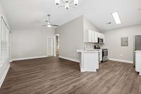 A spacious kitchen with white cabinets and a wooden floor.