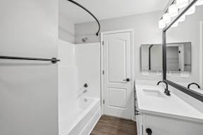 A white bathroom with a white tub and sink.